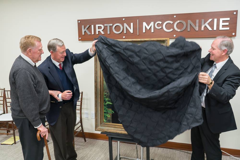 Oscar W. McConkie, Jr. looks as sons Oscar W. McConkie, III (left) and Daniel S. McConkie (right) reveal portrait to audience