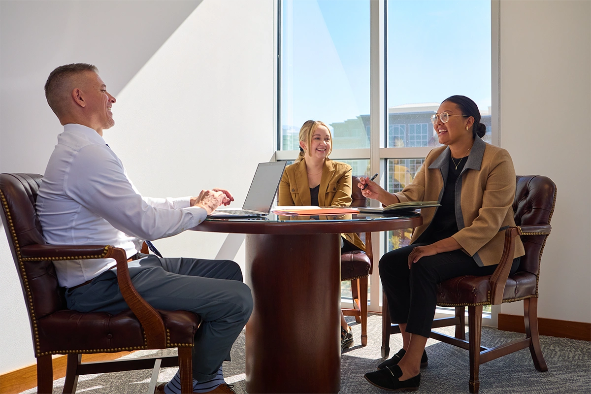 Three lawyers from Kirton McConkie discussing legal solutions at a round table.
