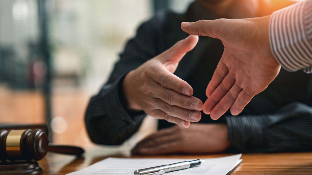 Business handshake over signed agreement and gavel, representing a merger and acquisition deal with a Boise business attorney