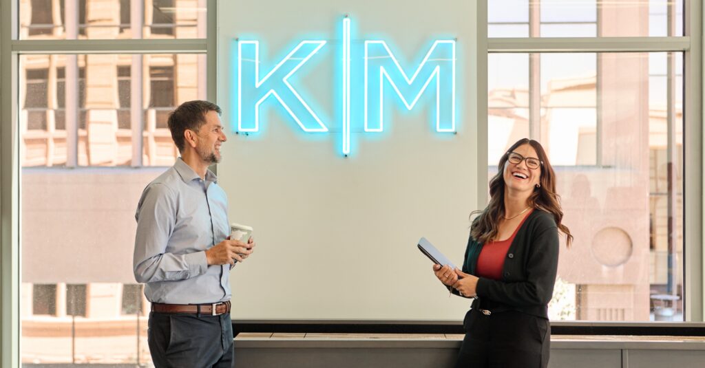 Best Companies to Work For article cover of two Kirton McConkie employees laughing in front of KM sign
