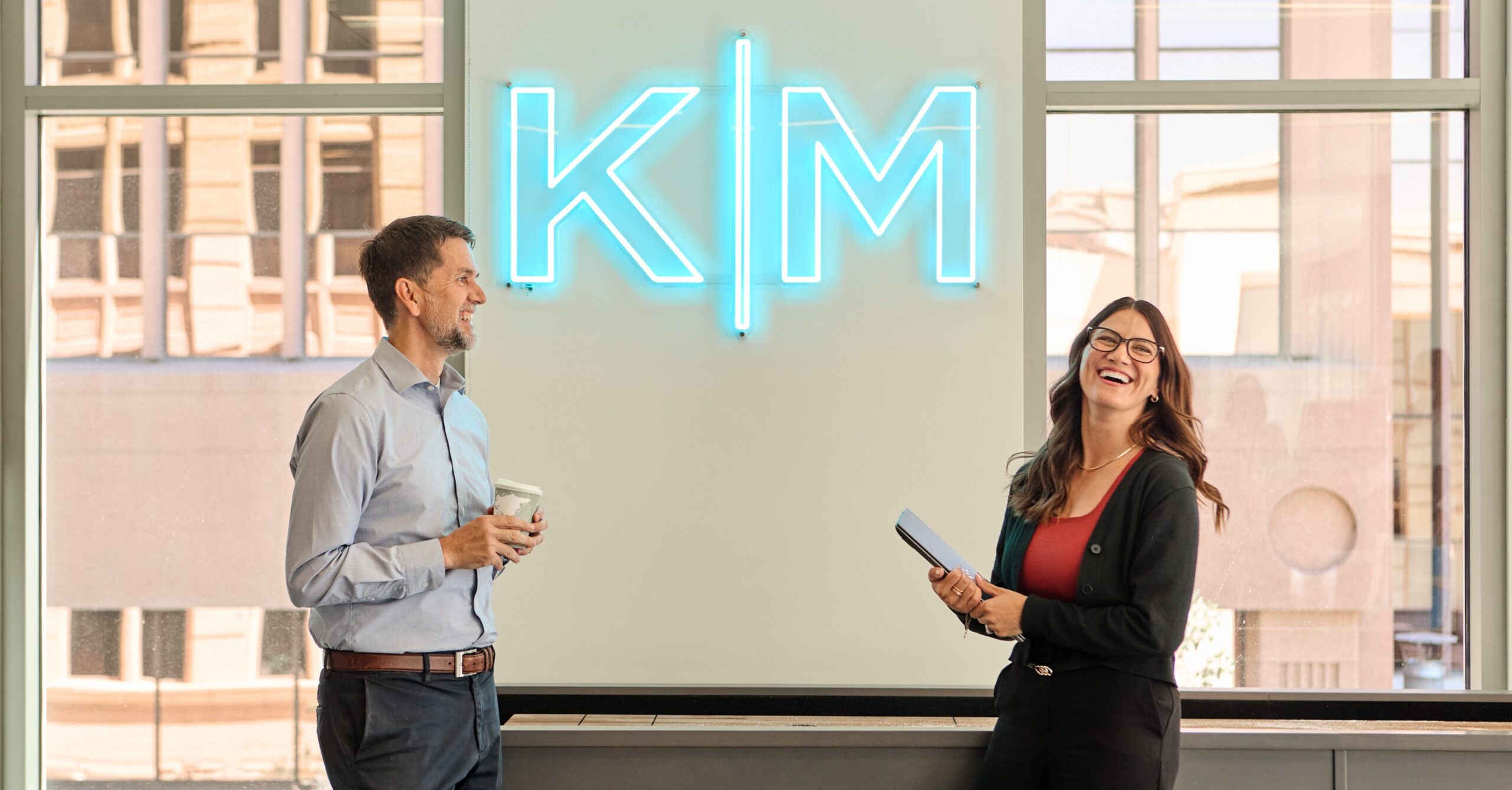 Best Companies to Work For article cover of two Kirton McConkie employees laughing in front of KM sign